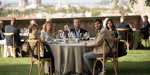 Alcuni dei protagonisti del film Ricchi a tutti i Costi seduti attorno a un tavolo