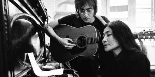 Una foto in bianco e nero che ritrae John Lennon e Yoko Ono al pianoforte